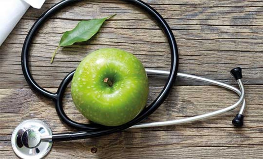 Krankenzusatzversicherung - Stetoskop, Blatt und Apfel auf Tisch